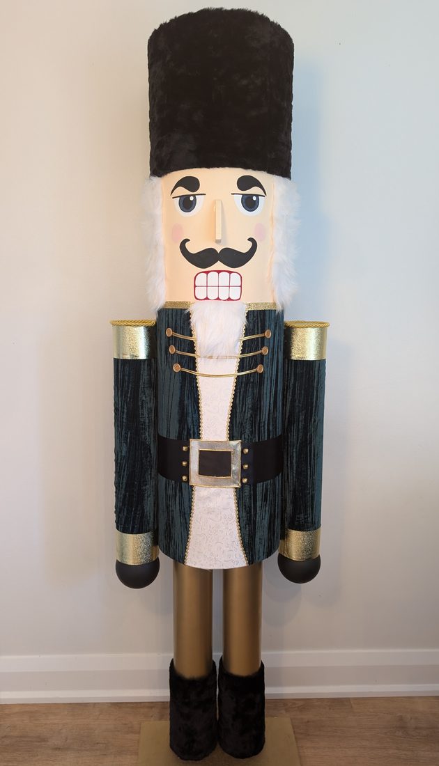 The Everhall nutcracker in teal velvet, standing about six feet tall in a living room